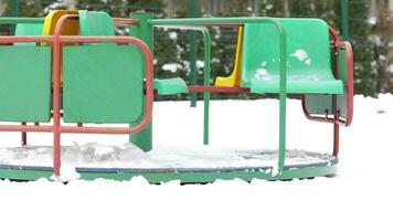 a green and yellow merry go round is covered in snow video