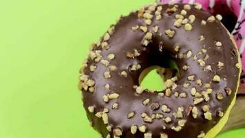 deux beignets avec rose et Chocolat Glaçage sur une vert Contexte video