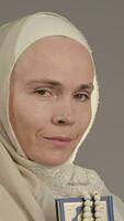 en kvinna i en hijab innehav en bön bok och bön pärlor video