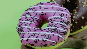 two donuts with pink and chocolate frosting on a green background video