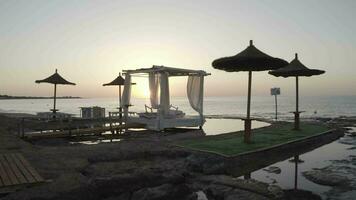 uma de praia com guarda-chuvas e uma pequeno piscina às pôr do sol video