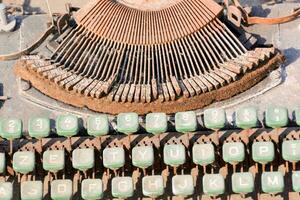 an old typewriter with green keys and a rusty metal frame photo