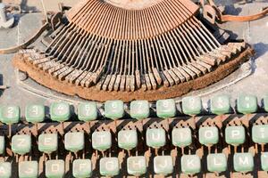 un antiguo máquina de escribir con verde llaves y un oxidado metal marco foto