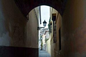 a narrow alley with a light on the end photo