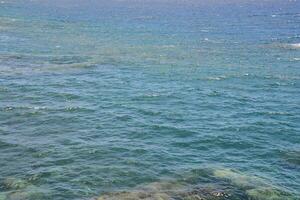 the ocean is blue and clear with rocks underneath photo