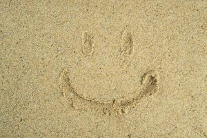 smile symbol drawn on the sand photo