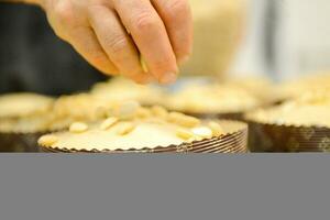 cocinero productor Panettone, mientras lievitar, agregando almendra azúcar Adición a crudo dulce un pan. foto