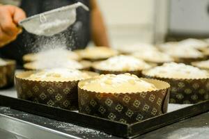 cocinero productor Panettone, mientras lievitar, agregando almendra azúcar Adición a crudo dulce un pan. foto