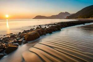the sun sets over a beach with rocks and water. AI-Generated photo