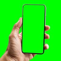 hand shows mobile smartphone with green screen in vertical position isolated on green background. Mock up mobile photo