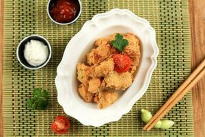 Chicken Karaage on White Bowl with Tomato and Parsley photo