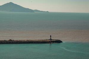 Lighthouse on the coast of the sea with mountains in the background photo