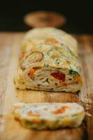 Omelet stuffed with vegetables and cheese on a wooden board. photo