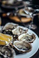 Fresh oysters on a plate with lemon and ice, selective focus photo