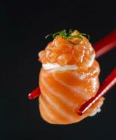 salmón nigiri Sushi en un negro antecedentes con rojo palillos foto