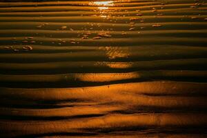 Sunset on the beach with golden sand and reflection in the water photo