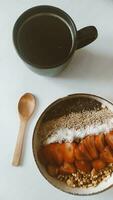 Cup of coffee with granola and strawberry on white wooden table photo