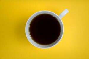 Cup of coffee on a yellow background. View from above. photo