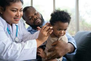 Pediatric doctor examining ear for a hearing test examining cute little girl in medical healthcare hospital or clinic. Smiling African American Baby whit pediatrician in hospital photo