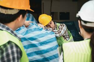 Foreman user radio to nurse for first aid Construction worker faint in construction site because Heat Stroke. Worker with safety helmet take a nap because so are tired from working in the hot sun photo