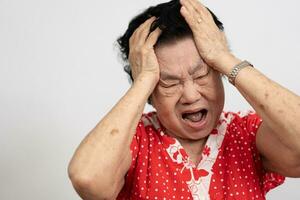 A senior woman who has a severe headache suffers from a stroke ,brain disease,patient holding head with her hand,suffering from senile dementia,memory disorders, confused old elderly with Alzheimer photo