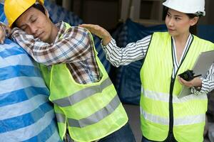 Foreman user radio to nurse for first aid Construction worker faint in construction site because Heat Stroke. Worker with safety helmet take a nap because so are tired from working in the hot sun photo