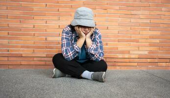 pobre cansado estresado Deprimido mayor asiático mujer Vagabundo sentado en el calle en el sombra de el edificio y mendicidad para ayuda y dinero, mayor asiático mujer abandonado concepto foto