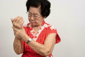 mayor asiático mujer pacientes sufrir desde entumecimiento dolor en manos desde reumatoide artritis. mayor mujer masaje su mano con muñeca dolor. concepto de articulación dolor, reumatoide artritis, y mano problemas. foto