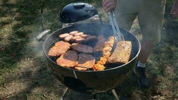 en man utomhus grillar kött på de utegrill video