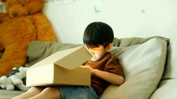 asiatisch Junge glücklich öffnet Geschenk Kasten. 4k Auflösung. video