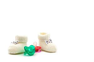 Knitted baby booties with bows in black polka dots and turquoise and pink pacifiers on isolated white background. Background. For text. For design. High quality photo