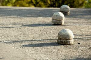 Gray concrete hemispheres obstructing traffic on gray asphalt. Sunny day, shadows on the asphalt. Montenegro. Budva. Horizontal. High quality photo. photo