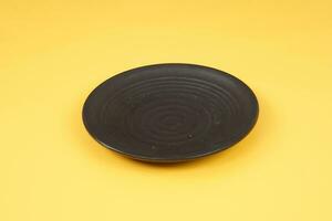 Black plate isolated on yellow background photo