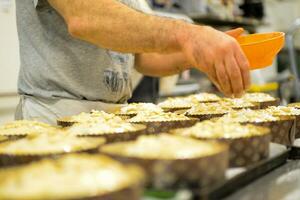 chef producing panettone, while lievitate, adding almond sugar topping to raw sweet bread. photo