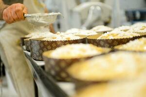 chef producing panettone, while lievitate, adding almond sugar topping to raw sweet bread. photo