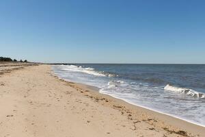 I loved the look of this beach as the waves battered the shore. The whitecaps of the waves make it look rough. The beautiful blue sky with no clouds in site make this look like a beautiful summer day. photo