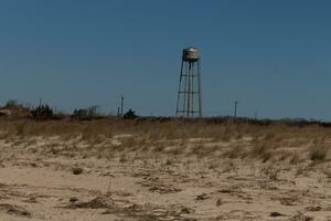 This beautiful beach image was taken at Sunset Beach in Cape May New Jersey. I love the look of the sand dunes at this location and the pretty brown sand. The water tower sits in the background here. photo