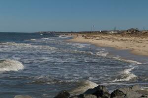 yo amado el Mira de esta hermosa playa escena. con bonito arena dunas. el agua golpeando el apuntalar con mira de áspero mares whitecaps ondulación mediante con bonito azul cielo. foto