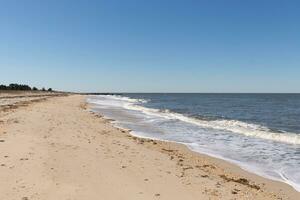 I loved the look of this beach scene as the waves crashed in. The pretty look of the whitecapped surd rushing in to the shore. The sand showing different tone to where the water once was. photo