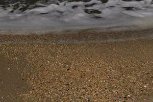 yo amado el Mira de el Oceano viniendo dentro el playa aquí. el mar espuma despacio Lavado terminado el bonito guijarros algunos de cuales Mira me gusta gemas y son translúcido todas muy suave desde siendo cayó. foto