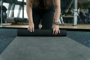 Fitness woman folding exercise mat before working out in yoga studio. rolling Yoga mat  after training healthy lifestyle photo