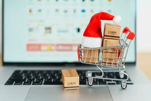 Christmas Online Shopping concept. Boxes with shopping cart on a laptop computer. Sale and discount during Christmas and New Year holiday, ecommerce, shipping delivery, logistics and Cyber Monday photo