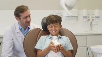 Happy little boy showing thumbs up after successful dental checkup with dentist video