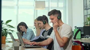 vriendelijk jong Mens glimlachen naar de camera, werken Bij klant ondersteuning telefoontje centrum video