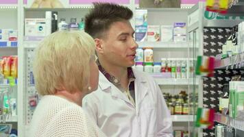 alegre masculino farmacêutico ajudando idosos fêmea cliente video