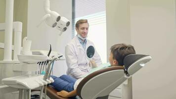 alegre pequeño chico y su dentista sonriente a el cámara video