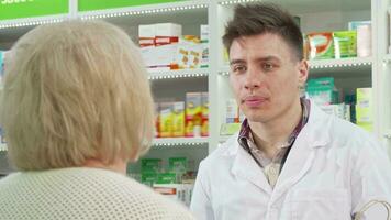 Handsome young pharmacist handing shopping bag with purchase to a customer video