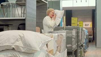 Senior female customer choosing new orthopedic pillow at furnishings store video