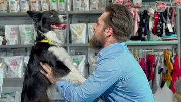 feliz barbudo homem jogando com dele cachorro às veterinário escritório video