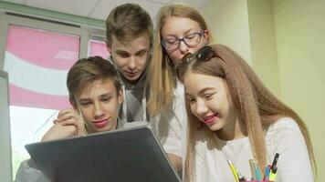 Low angle cropped shot of group of teens studying together, using laptop video